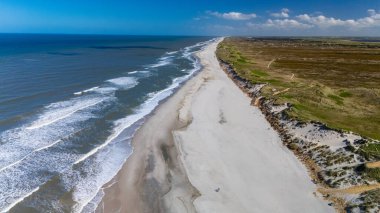 Danimarka 'nın sakin kumlu sahillerini keşfedin. Yumuşak dalgaların parlak mavi bir gökyüzünün altında kıyıları öptüğü..