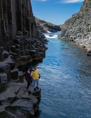 Ziyaretçiler İzlanda 'daki şaşırtıcı bazalt sütunlara ve Studlagil Kanyonu' nun berrak sularına hayret ediyorlar. Canlı manzara, dramatik manzaranın ortasına macera ve keşif davet ediyor..