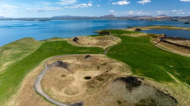 İzlanda 'da yemyeşil ve sakin göllerle çevrili Myvatn kraterlerinin nefes kesici manzarası. Eşsiz jeolojik oluşumlar açık mavi gökyüzünün altında başka bir dünya manzarası yaratıyor..