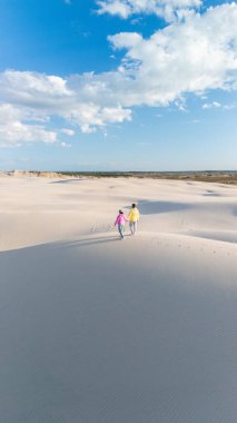 Güneşli bir günde Danimarka 'nın Rabjerg Mile bölgesindeki kumullarda el ele dolaşırlar. Açık mavi gökyüzü kabarık bulutlarla kaplı. Rahatlamak için mükemmel sakin bir atmosfer yaratıyor..