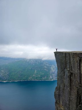 Cesur bir maceracı, Norveç 'in dik yamaçlarında, nefes kesici fiyortlarla çevrili bir uçurumun üzerinde muzaffer bir şekilde duruyor. Norveç 'in Önceki Uçurumu