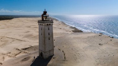 Rubjerg Knude Deniz Feneri 'nin Danimarka' nın geniş kum tepeleri ve köpüklü sularına karşı nefes kesici bir görüntüsü. Bu kıyı simgesi doğayla çarpıcı bir tezat sergiliyor..