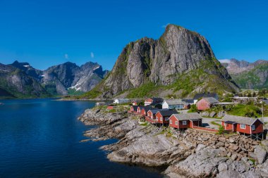 Dik dağlar ve kristal berrak sular arasında yer alan Lofoten 'de büyüleyici bir balıkçı köyü, canlı Norveç kültürünü yansıtan geleneksel kırmızı kulübelerini sergiliyor..