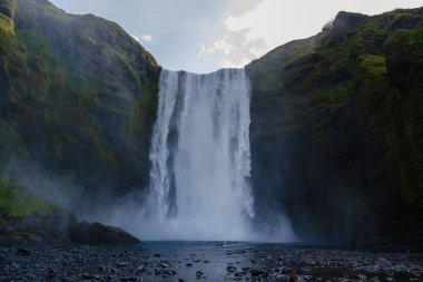 Su, Skogafoss şelalesi İzlanda 'nın kayalıklarından zarif bir şekilde düşer ve sisli bir atmosfer yaratır..