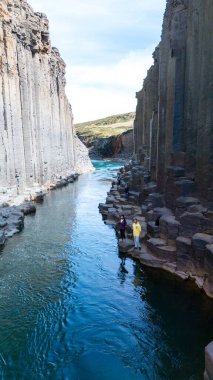 Ziyaretçiler, bazalt sütunlar ve sakin bir nehirle karakterize edilen çarpıcı Studlagil Kanyonu 'nu keşfediyorlar. Bu eşsiz jeolojik oluşum hayranlık uyandırıcı bir manzara sunuyor..