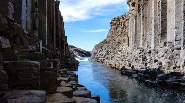 Majestic bazalt sütunları İzlanda 'daki Studlagil Kanyonu' nun sakin sularını çerçeveliyor. Bu eşsiz jeolojik mucize doğayı sergiliyor. Sanatçılık, maceracıları ve fotoğrafçıları güzelliğinden zevk almaya davet ediyor..