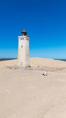 Rubjerg Knude deniz fenerinin güzelliğini deneyimleyin. Danimarka 'nın geniş kum tepeleri ve mavi gökyüzüne karşı dimdik ayakta duruyor..