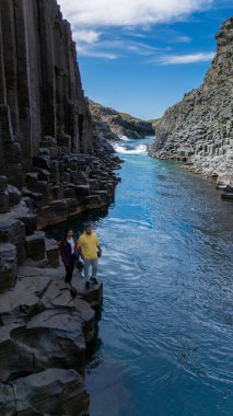 Ziyaretçiler, İzlanda 'daki Studlagil Kanyonu' nun nefes kesici kaya oluşumlarına ve turkuaz sularına hayran. Eşsiz bazalt sütunlar doğadaki maceralar için olağanüstü bir zemin oluşturur..