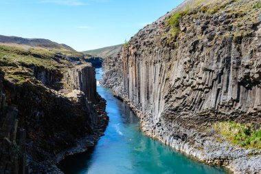 Studlagil Kanyonu 'nun nefes kesici güzelliğini deneyimleyin. Bazalt sütunlarının turkuaz nehrin yanında yükseldiği yer. İzlanda 'da huzurlu manzaralar arayan doğa severler ve maceracılar için ideal..