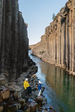 Maceraperest yürüyüşçüler nefes kesici Studlagil Kanyonu 'nda dolaşır. Etrafı bazalt sütunlar ve sakin bir nehirle çevrilidir. Bu eşsiz jeolojik oluşum İzlanda 'nın doğal harikalarını sergiliyor..