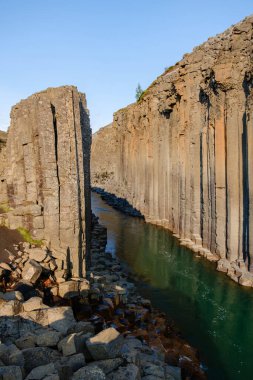 İzlanda 'daki Studlagil Kanyonu' nda bazalt sütunlar ve içinden akan sakin bir nehir bulunur. Ziyaretçiler nefes kesici manzaraların keyfini çıkarabilir ve gün batımında çarpıcı jeolojik oluşumları keşfedebilirler..