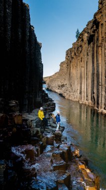 İki maceraperest, İzlanda 'daki Studlagil Kanyonu' nun büyüleyici bazalt sütunlarında dolaşır. Etrafında muhteşem kaya oluşumları ve sakin bir nehir bulunur. 