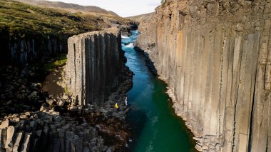 İzlanda 'nın göbeğine yerleşen Studlagil Kanyonu, eşsiz bazalt sütunları ve canlı turkuaz nehri ile büyülenir. Maceracılar güneşli bir günde bu doğa harikasını keşfederken görülebilir..