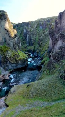 İzlanda 'daki Fjadgljufur Kanyonu' nun nefes kesici güzelliğini keşfedin. Kristal berrak suların üzerinde dramatik uçurumlar yükselir..