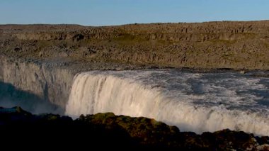 Dettifoss şelalesi İzlanda 'daki dik uçurumlardan aşağı yuvarlanarak puslu bir sprey oluşturur ve doğanın saf güzelliğini gözler önüne serer. Güneş ışığı çevredeki dramatik araziyi vurguluyor..