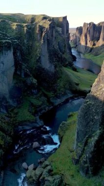 İzlanda 'daki Fjadrargljufur Kanyonu' nun büyüleyici doğal özelliklerini tecrübe edin. Dik kayalıkların yemyeşil ile buluştuğu ve altın saat boyunca ışıldayan bir nehrin muhteşem manzarada aktığı yer..