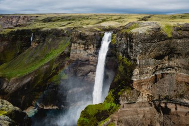 Haifoss nefes kesici şelalesi engebeli kayalıklar ve dramatik İzlanda arazisi tarafından çerçevelenmiş canlı yeşil bir vadiye daldı. Bu resim gibi manzara doğanın güzelliğini yansıtıyor..
