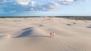 Danimarka 'nın Rabjerg Mile kentindeki geniş kum tepelerinde el ele dolaşırlar. Altın saat boyunca. Hafif bir ışık ve hafif bir esinti sakin bir atmosfer yaratır.