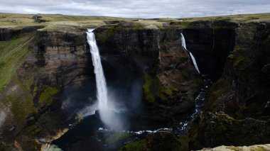 Su sarp kayalıklardan, yemyeşil sularla çevrili sakin bir havuza çarpar. Haifoss şelalesi İzlanda