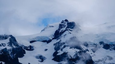 İzlanda 'nın çarpıcı doğa harikası Svinafellsjokull Buzulu' nu keşfedin. Etrafı dramatik dağlar ve puslu bulutlarla çevrili. Bu ikonik buzulun güzelliğini hissedin..