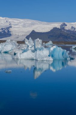 Jokulsarlon Buzul Gölü 'nün kristal berrak suları görkemli buzdağlarını ve etrafındaki dağları yansıtır. Nefes kesici bir manzara İzlanda 'da gün ışığında güzelliği gözler önüne seriyor..