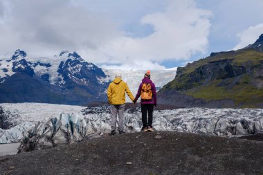İki kişi el ele durarak İzlanda 'daki şaşırtıcı Svinafellsjokull Buzulu' na hayran kaldılar.