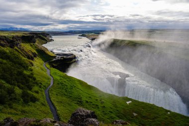 Gullfoss şelalesinin ihtişamına tanık olun. Hvita nehrine çarpıcı bir şekilde yuvarlanıyor, yemyeşil tepelerle çevrili. İzlanda 'da çekilen nefes kesici doğa gücü..