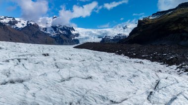 İzlanda 'daki Svinafellsjokull Buzulu' nu araştırıyoruz. Orada engebeli dağlara ve açık mavi gökyüzüne karşı devasa buz oluşumları var. Görkem ve güzelliğin mükemmel bir örneği..