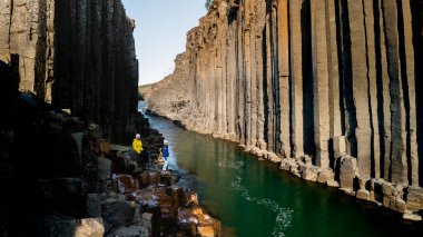 Ziyaretçiler İzlanda 'daki muhteşem Studlagil Kanyonu' nu keşfediyorlar. Etrafı bazalt sütunlar ve canlı sularla çevrili. İzlanda 'da tatilde olan birkaç erkek ve kadın.