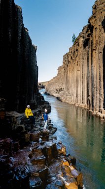 Ziyaretçiler İzlanda 'daki Studlagil Kanyonu' nun çarpıcı güzelliğine hayret ediyorlar. Yükselen bazalt sütunlar canlı mavi nehir boyunca uzanır, doğa severler ve maceracılar için benzersiz bir manzara yaratır..