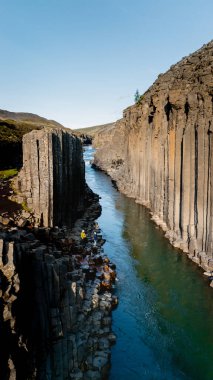 İzlanda 'da bulunan Studlagil Kanyonu' nda kristal berraklığında bir nehri çevreleyen nefes kesici bazalt sütunlar bulunuyor. Ziyaretçiler parlak mavi gökyüzünün altında bu jeolojik mucizeyi keşfeder, güzellikleri gözler önüne serer..