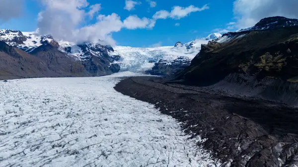 İzlanda 'daki Svinafellsjokull Buzulu' nun süpürülen manzaraları üzerinde parlak mavi gökyüzü olan buz ve kayaların çarpıcı bir etkileşimini ortaya koyuyor. Bu dingin ortam keşif ve maceraya davetiye çıkarıyor..