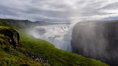 Su Gullfoss Şelalesi 'nin kenarından dramatik bir şekilde düşer. Etrafı yeşil kayalıklar ve sisle çevrilidir. Sabahın erken saatleri gizemli bir atmosfer yaratır, keşifleri davet eder..