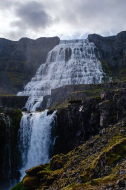 Sarp kayalıkların üzerinden akan muhteşem şelalenin nefes kesici manzarasına tanık olun. Etrafı yemyeşil yosunlar ve kayalık arazilerle çevrili. Dynjandi şelalesi, Westfjord, İzlanda.