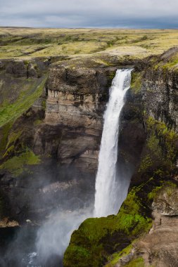 Haifoss şelalesi İzlanda 'daki yemyeşil kayalıklarla çevrili sakin bir havuza dalıyor. Dramatik arazi ve bulutlu gökyüzü doğa aşıkları için mükemmel, çarpıcı bir doğal manzara yaratır..