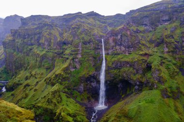 İzlanda 'daki Mulagljufur Kanyonu' nun nefes kesici güzelliğini deneyimleyin. Kayalık kayalıklardan yükselen çarpıcı bir şelale, canlı yeşil tepelerle çevrili. Doğa başyapıtı burada sergileniyor..