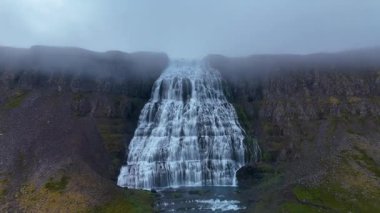 Dynjandi şelalesinin nefes kesici güzelliğine tanık olun. Suyun, sisli bir günde İzlanda 'nın sakin manzarasıyla çevrili yosun kaplı kayaların üzerinde zarifçe aktığı yere..