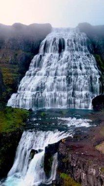 İzlanda 'daki görkemli Dynjandi şelalesine tanık olun. Su, verimli kayalıkların üzerinden dramatik bir şekilde akıyor. Sisli manzaranın ortasındaki bu büyüleyici yerin dingin güzelliğini ve doğal güzelliğini keşfedin..