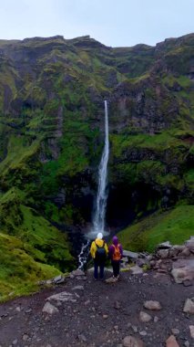 İki maceraperest, Mulagljufur Kanyonu 'nun kayalıklarından dökülen muhteşem şelaleye huşu içinde bakar..