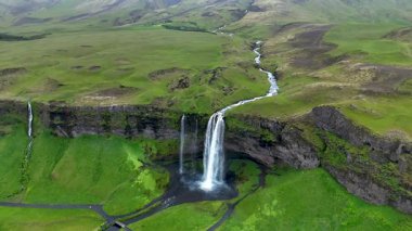 Uzun Seljalandsfoss şelaleleri yosunlu kayalıklardan İzlanda 'daki dingin bir havuza dalarlar ve çarpıcı bir doğa güzelliği sergilerler. Bölgeyi çevreleyen yemyeşil tepeler dramatik manzarayı güçlendiriyor.