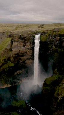 Soluk kesici Seljalandsfoss şelalesinin dramatik bir uçurumdan yuvarlanışına tanık olun, bulutlu bir gökyüzü altında yemyeşil manzaralarla çevrili, İzlanda 'nın eşsiz güzelliğini gözler önüne seriyor..