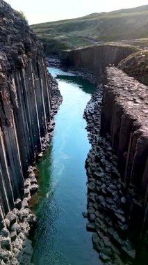 İzlanda 'daki Studlagil Kanyonu' nun nefes kesici güzelliğini deneyimleyin. Bazalt sütunları sakin bir nehir boyunca uzanır. Yıl boyunca ziyaretçileri cezbeden çarpıcı jeolojiyi ve doğayı keşfedin..