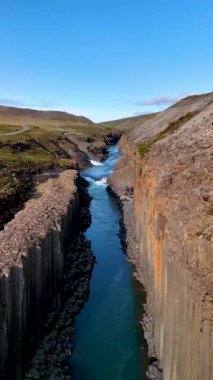 İzlanda 'daki Studlagil Kanyonu' nun güzelliğini keşfedin. Nehirden baş döndürücü bazalt sütunlar yükseliyor..