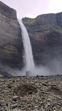 Haifoss şelalesinin gücünü keşfedin. Kayalık kayalıkların üzerinden düşerken, İzlanda 'nın büyüleyici doğasıyla çevrili. Sis yükselir, gri gökyüzünün altında ruhani bir atmosfer yaratır..