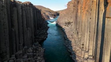 İzlanda 'nın uzak dağlık bölgelerine yerleşmiş Studlagil Kanyonu nefes kesen bazalt sütunları ve derinlerinden akan canlı mavi bir nehirle büyülenir..