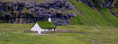 Faroe Adaları 'ndaki sarp, yeşil uçurumların önünde otlak bir çatısı olan tuhaf bir kulübe duruyor. Bu dingin ortam Saksun köyünün İskandinav sükunetinin özünü yansıtıyor.