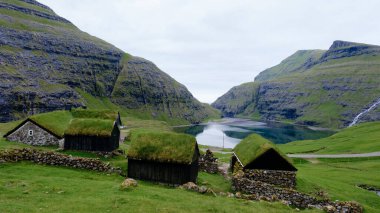 Çarpıcı uçurumlar ve sakin sular arasında yuva yapmış, Faroe Adaları 'ndaki ilginç otlak çatılı evler manzarayı süslüyor. Saksun Köyü