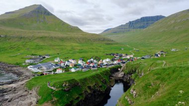 Gjogv, yüksek dağlar ve yemyeşil tepeler arasına yerleştirilmiş geleneksel Faroe mimarisini sergiliyor. Canlı köy, bu uzak yerin zengin kültürünü ve manzaralı güzelliğini yansıtıyor..