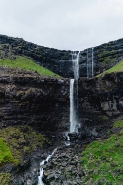 Fossa şelalesi, büyüleyici Faroe Adaları 'ndaki canlı yeşil çimenler ve kayalık araziyle çevrili engebeli uçurumlardan aşağı yuvarlanır. Bu dingin doğa harikası macerayı davet ediyor..