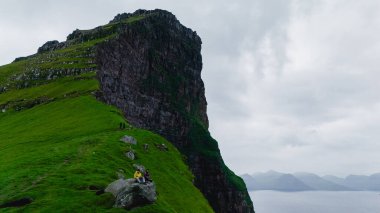 Serüvenciler, yemyeşil manzaralar ve dramatik kaya oluşumlarıyla çevrili Faroe Adaları 'nın çarpıcı uçurumları boyunca yürüyüş yaparlar. Kallur Deniz Feneri Kalsoy Adası